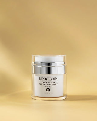 Skincare cream jar labeled 'Hrda Skin'  Apple Cheeks All Day and Night Creme on a gold background