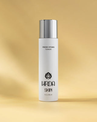 White toner bottle with silver cap on a gold background Labeled Fresh Stems by Hrda Skin