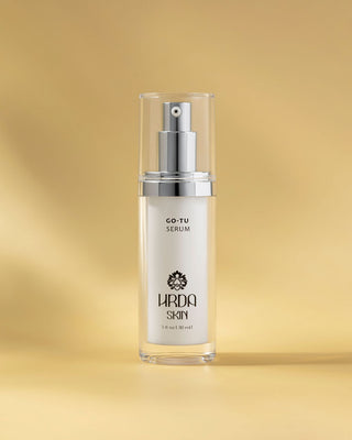 Go-Tu Serum bottle with silver cap on a gold background by Hrda Skin