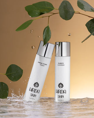 Hrda Skin cleanser and toner in splashing water with eucalyptus leaves on gold background.