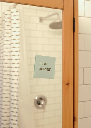 Blue note on bathroom mirror reads love yourself.